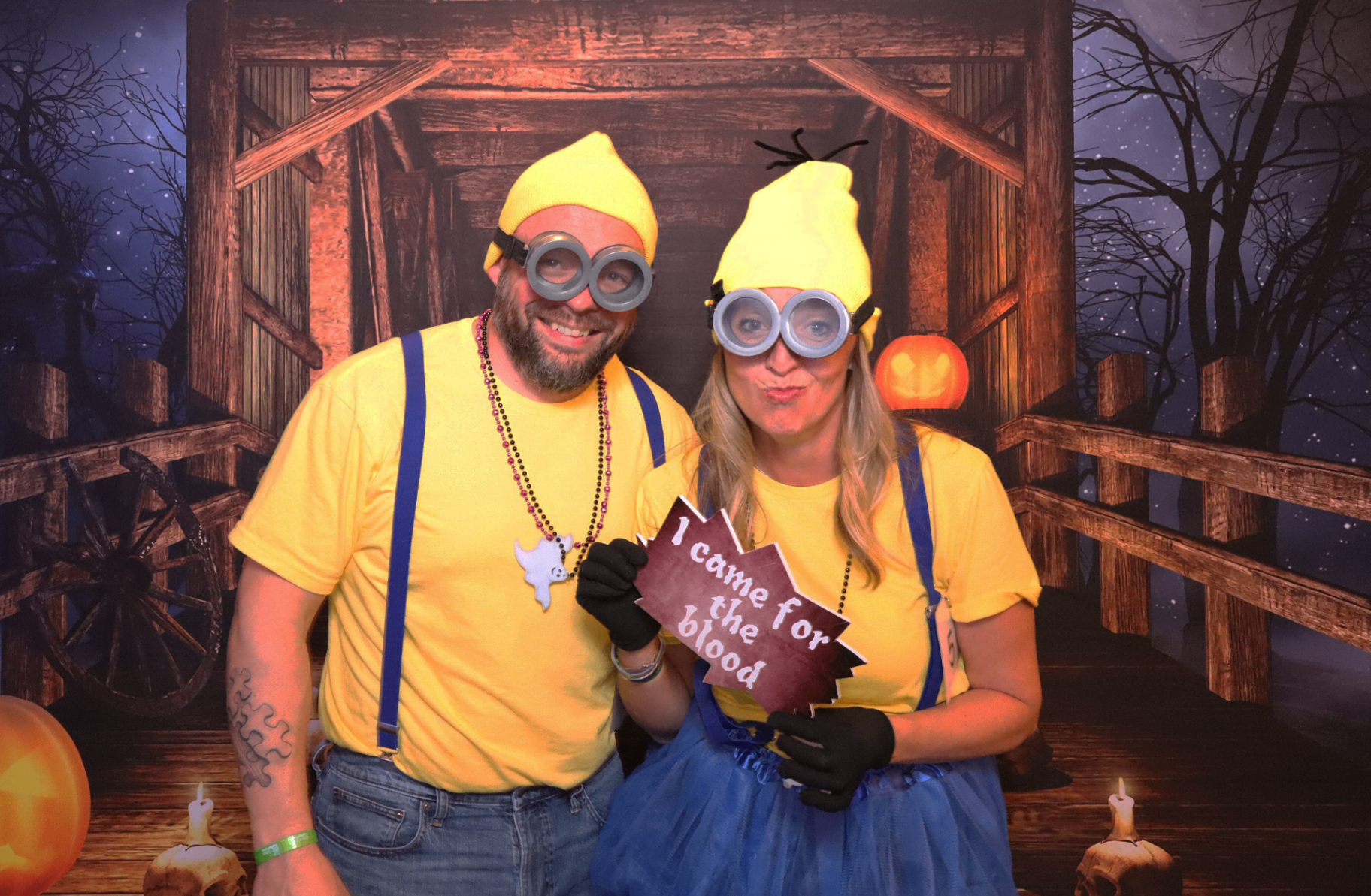 Two guests dressed as Minions in front of a spooky Halloween backdrop at a company costume party