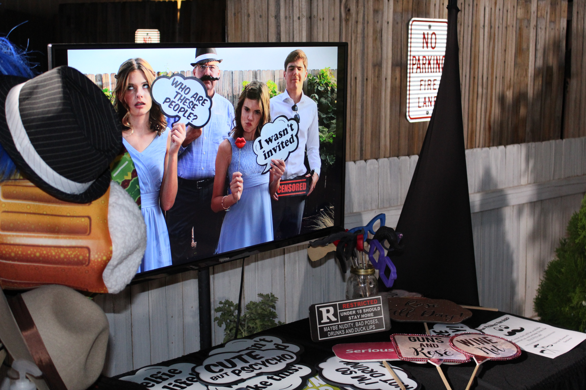 Outdoor wedding photo booth setup with props and live slideshow display