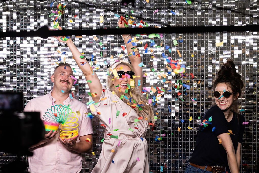Guests celebrating with confetti in front of a silver shimmer wall