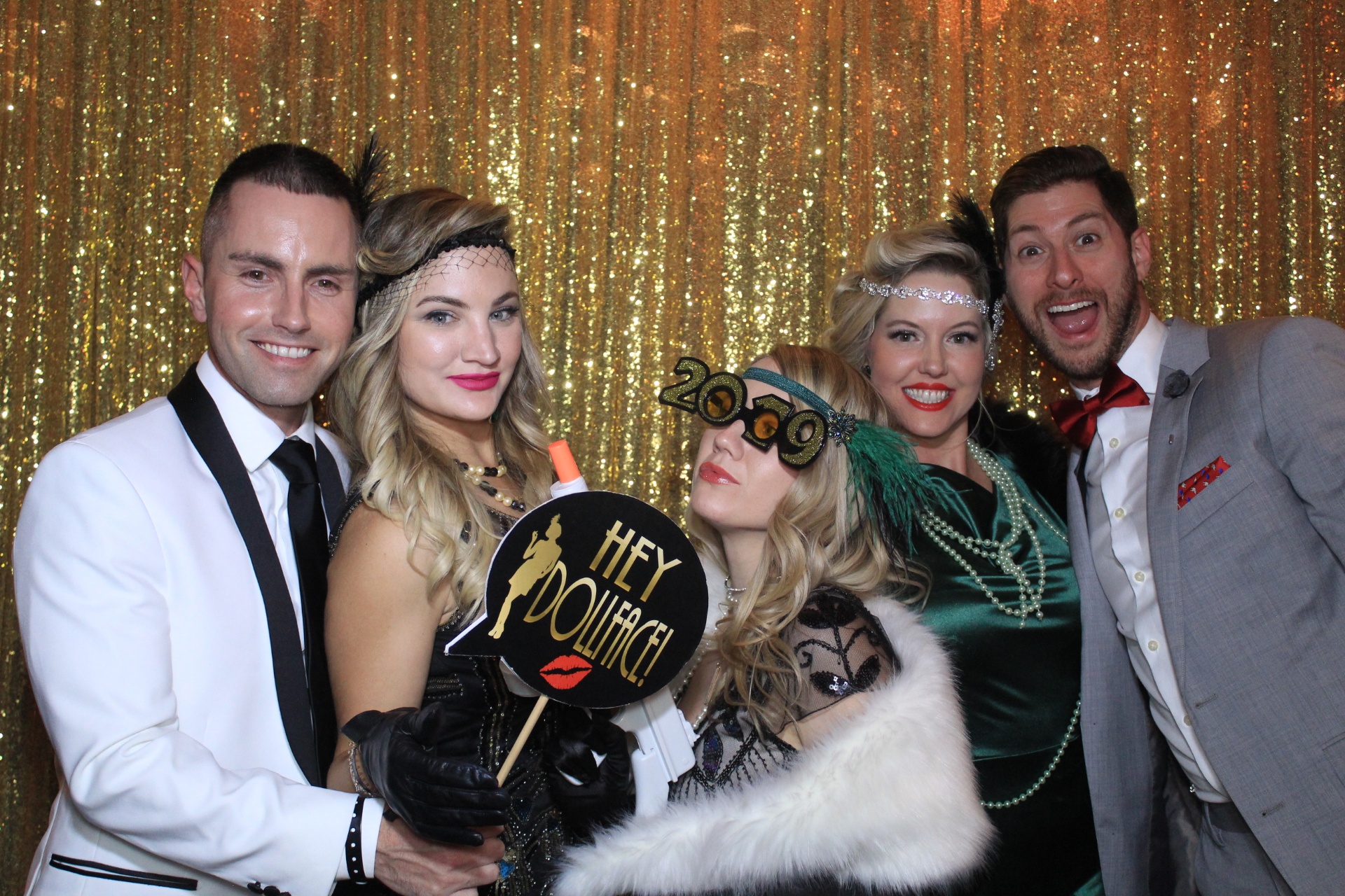 Guests dressed in festive Gatsby attire celebrating at a gold sequin corporate event
