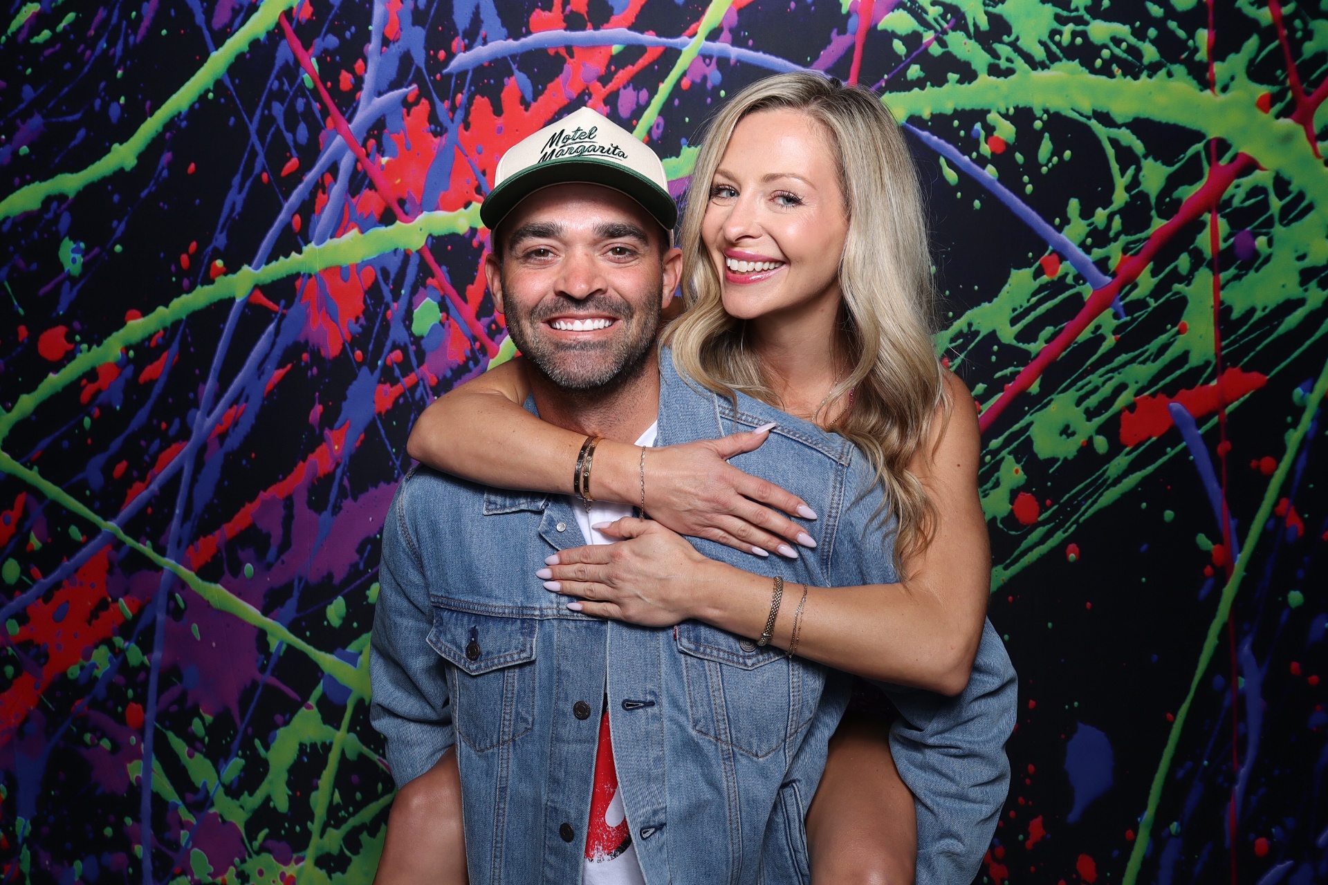 Couple posing against a neon splatter backdrop